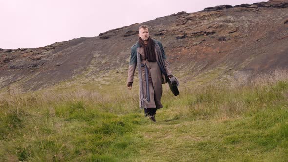 Stylish Man with a Sack Bag and a Banjo Case Walks Along the Green Meadow alt