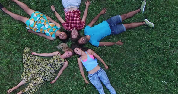 Beautiful young friends forming a star shape lying in grass alt
