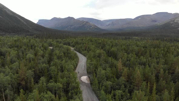 A Top View From the Drone of a Dirt Road in a Dense Forest Near the Mountains alt