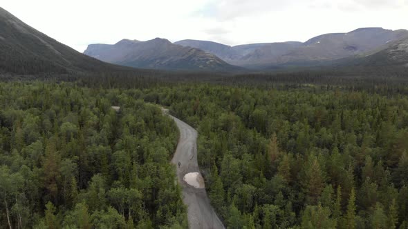 A Top View From the Drone of a Dirt Road in a Dense Forest Near the Mountains