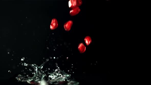 Super Slow Motion Pomegranate Grains Fall Into the Water with Splashes alt
