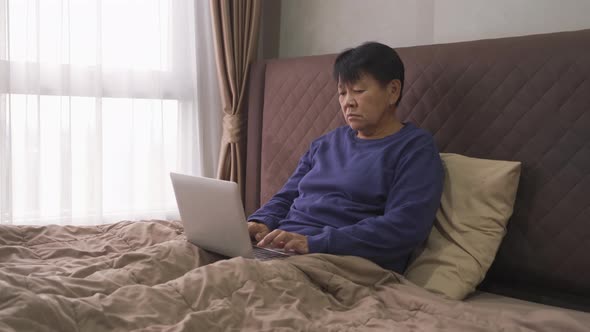 Depressed elderly old Asian woman, people using a notebook laptop computer on social media