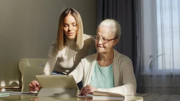 Grandmother Learning Digital Tablet with Help of Young Woman