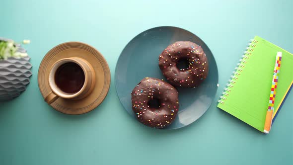 Chocolate Donuts  Tea and Notepad on Table alt