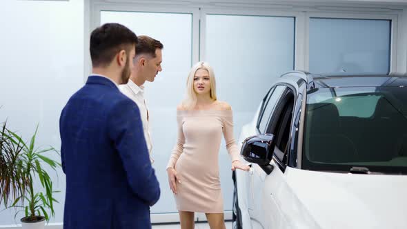 Pretty Young Elegant Couple Choosing Car in Dealership alt