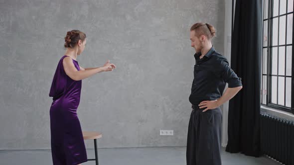Man Teaching Woman Dancing Tango in Grey Studio Against Large Windows