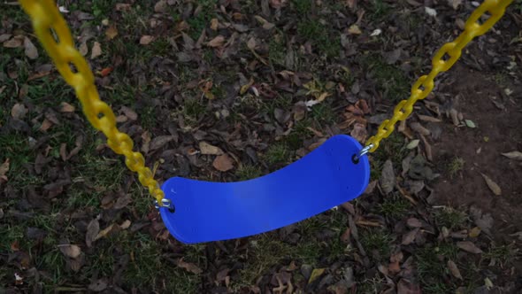 Blue swing hanging from yellow chain alt