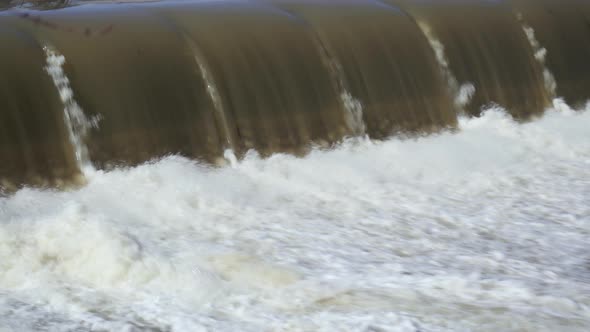 UHD Long shot of water rushing away from the base of a small waterfall during a spring melt alt