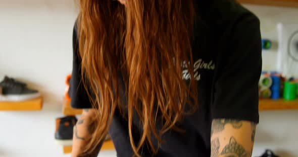 Front view of young caucasian woman applying skateboard grip tape in workshop 4k alt