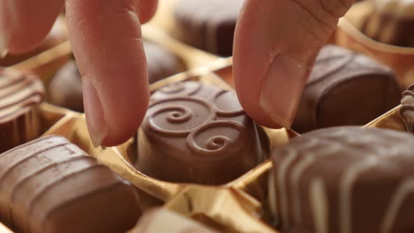 Package box picking one of lot  chocolates  4K 2160p 30fps UltraHD footage - Hand pick  gift assorte alt