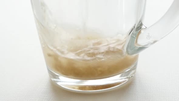 Water added to granulated tea in a glass slow motion video