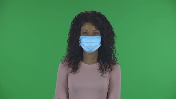 Portrait of Beautiful African American Young Woman in Medical Mask Is Looking Straight and Talking alt