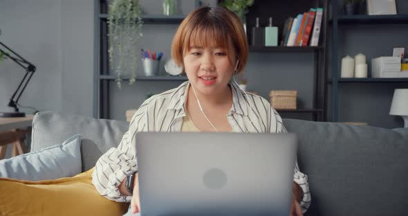 Asia businesswoman using laptop talk to colleagues about plan in video call while working from house
