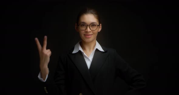 Asian Woman in Glasses Smiling and Shows Two Fingers with Her Right Hand