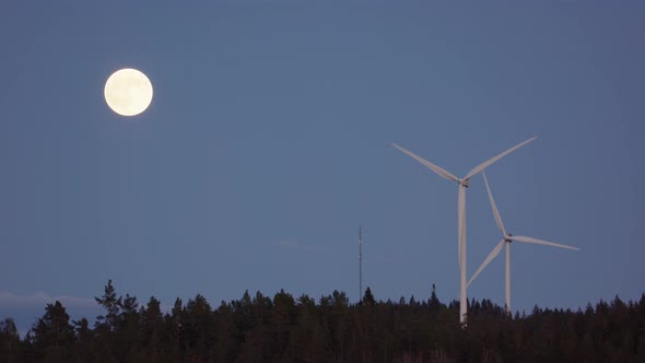 FULL MOON, SLOW MOTION - Wind turbines spin next to a rising full moon alt