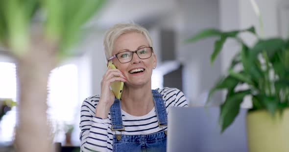 Mature woman sitting at table making a phone call
