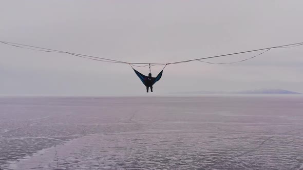 Silhouette of a Man in a Hammock Mounted at High Altitude