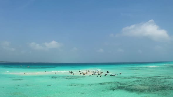 Anchored boats and people in shallow tropical ocean sandbank, Zanzibar. alt
