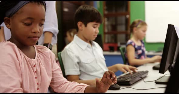 Teacher assisting school kids on personal computer in classroom alt
