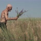 Elderly Man Walks on Wild Field and Holds Purple Flowers - VideoHive Item for Sale