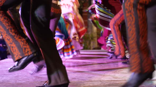 Closeup of men stomping their boots as women twirl their dresses in a Mexican folk dance. alt