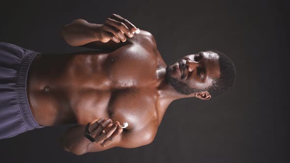 Closeup of a Darkskinned Man with Athletic Muscles on a Dark Background Listening to Music alt