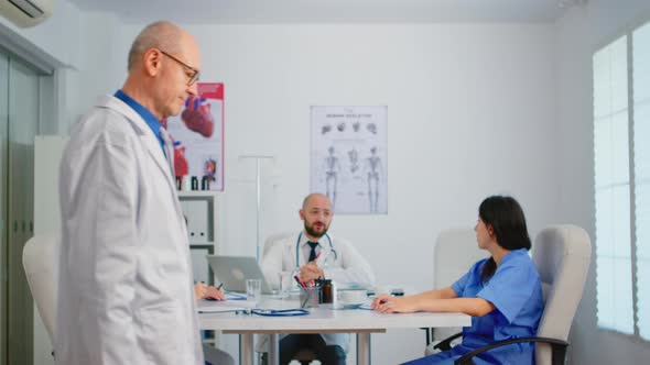 Portrait of Elderly Man Surgeon Standing in Front of Camera Smiling alt