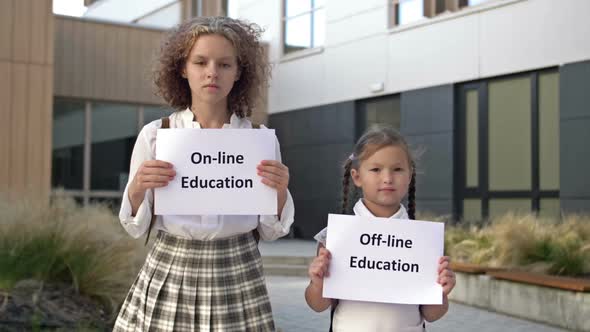 Two Schoolgirls with Placards are Standing in Front of the School Building