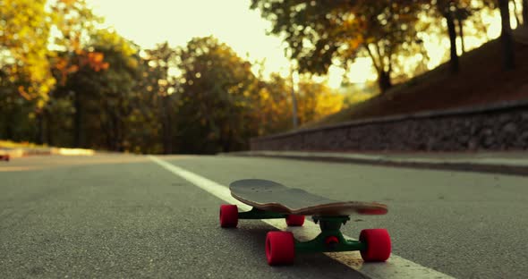 The Guy Jumps on a Longboard. Beautiful Summer Sunset alt