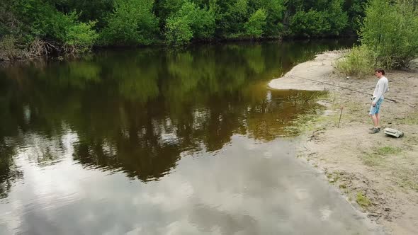 Aerial View of Fisherman with a Fishing Rod on the River Bank alt