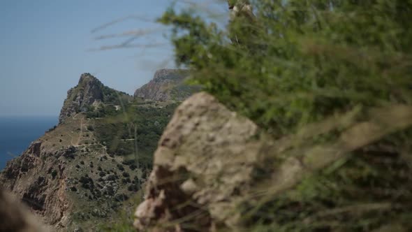 A Young Man in Brown Clothes on the Edge of a Cliff in a Lotus Pose alt