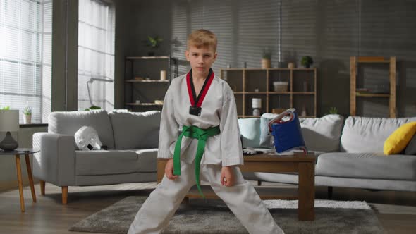 Karate Boy in White Kimono Trains at Home in the Living Room alt