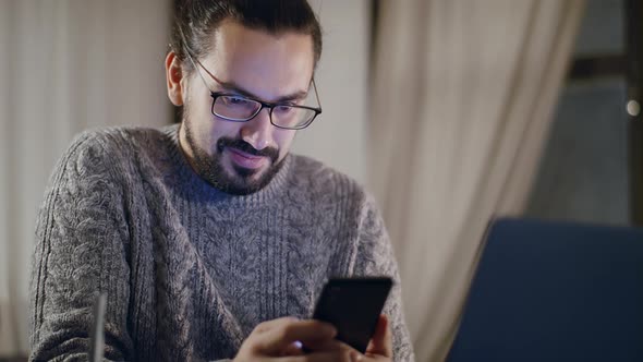A Man with Glasses in Front of a Computer Monitor in the Evening alt