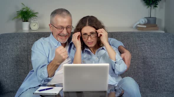 A Happy Middleaged Couple Looking at a Laptop Feels Like an Online Winner