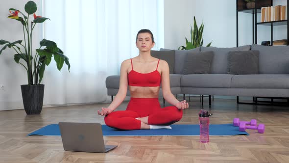 Beautiful Fit Girl Sits Meditating in Lotus Position on Sport Fitness Blue Mat alt
