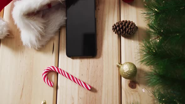 Video of christmas decorations with smartphone and santa hat on wooden background alt