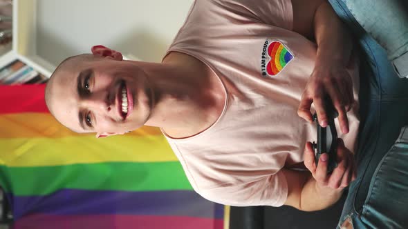 Vertical Indoor Shot of a Young Caucasian Queer Gay Gamer Playing Video Games with His Touch Pad alt
