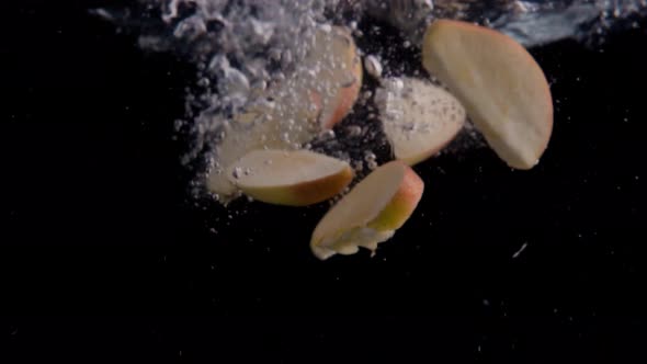 Apple Slices Falling into Water Super Slowmotion, Black Background, lots of Air Bubbles, 4k240fps alt