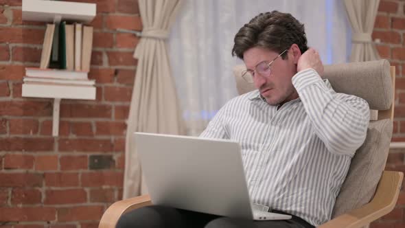 Middle Aged Man with Laptop having Neck Pain on Sofa alt