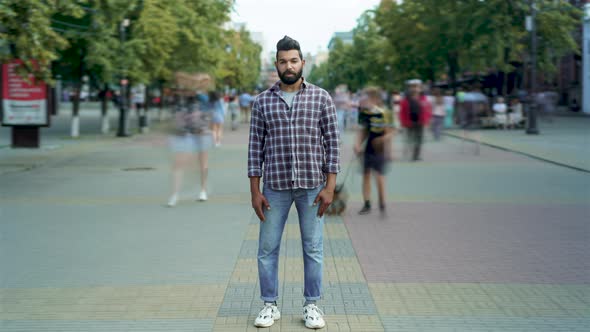 Time Lapse Portrait of Attractive Arab Man Standing Outside in Crowded Street Looking at Camera alt