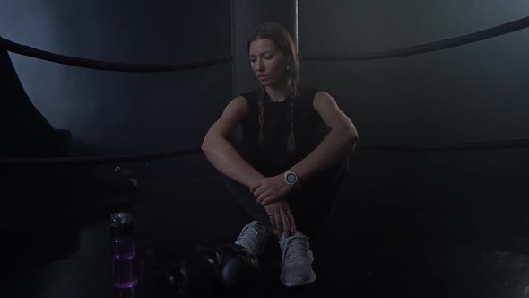 A Tired Woman Sits in the Corner of the Ring After a Workout