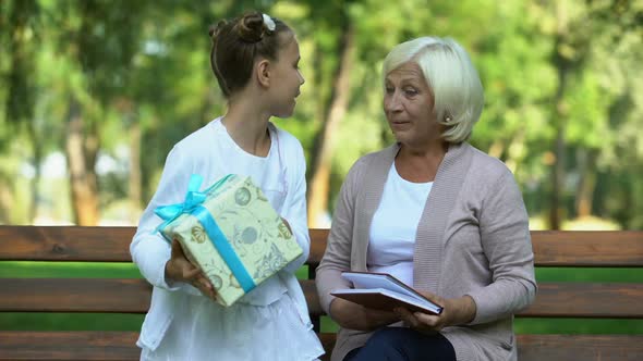 Little Girl Presenting Gift Box to Her Beloved Grandmother, Family Care and Love