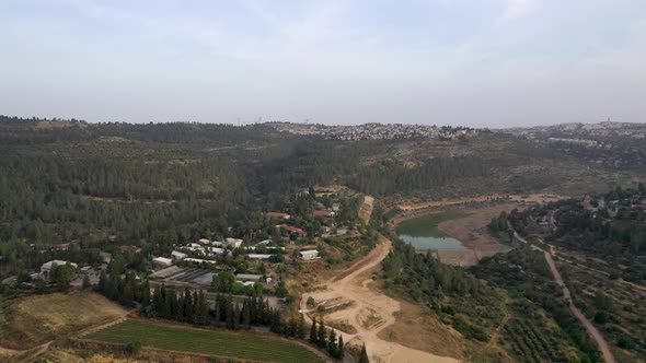 Aerial shot over small settlement inside a forested area in the Jerusalem mountains, drone shot alt