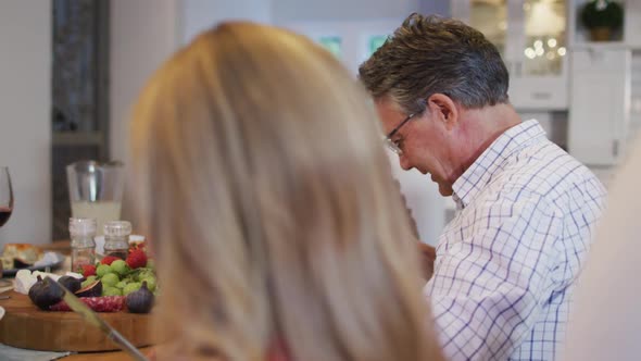 Happy caucasian grandfather smiling to granddaughter at table during family meal alt