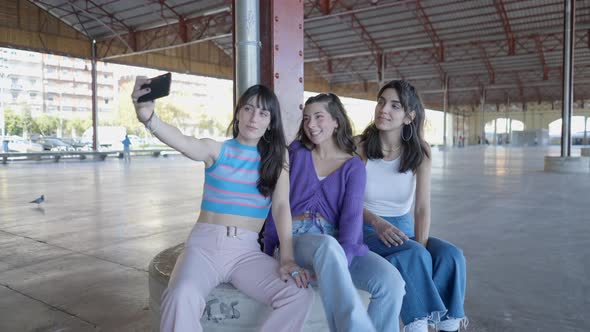 Three Happy Girls in Roller Skates Outdoors and Take Selfie with Phone alt