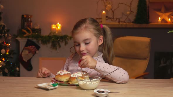 Little Girl Is Placing the Small Candles on the Delicious Cinnamon Rolls alt