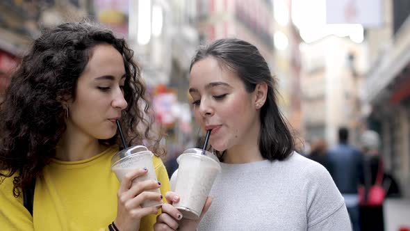 Two happy girls in Madrid drinking a milkshake