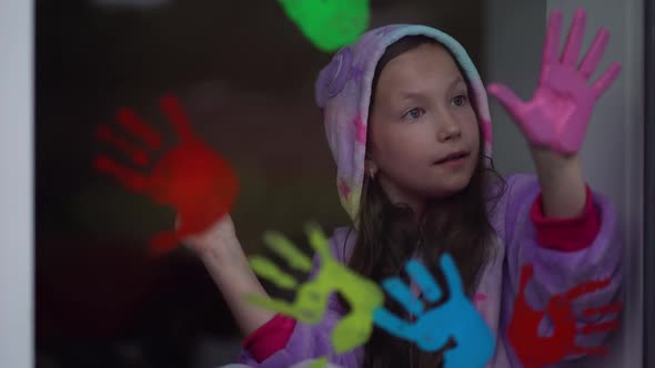 School Girl in Pajamas Paint with Palms on the Window. alt