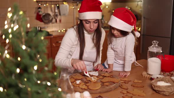 Adorable Little Daughter with Her Mom at Kitchen During Christmas Holidays alt