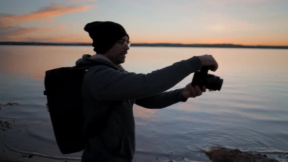 Photographer and Man Model Silhouette Taking Photos at the Lake Shore on Colourful Sunset Slowmotion alt